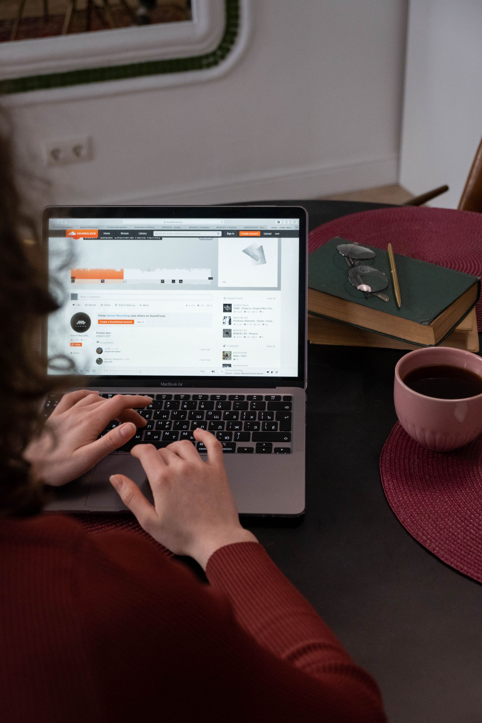 A person working on a laptop beside a notebook